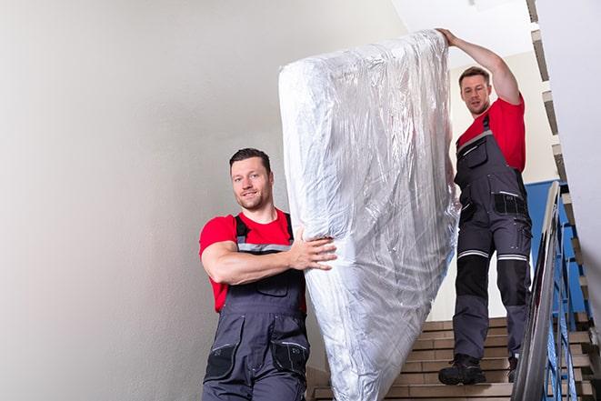 team of workers maneuvering a box spring through a doorway in Whitehall